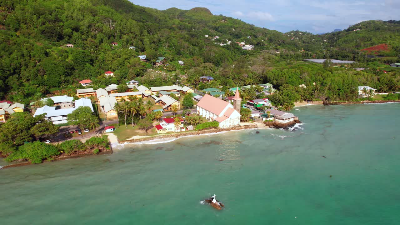drone de la iglesia de san josé cerca de la orilla de la playa de anse royale, cruz en la roca en el centro del océano, mahe, seychelles 30fps 1