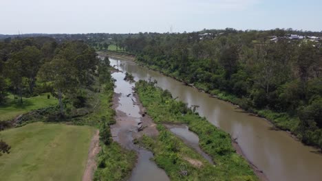 aerial view of a small brown river with private homes in the background