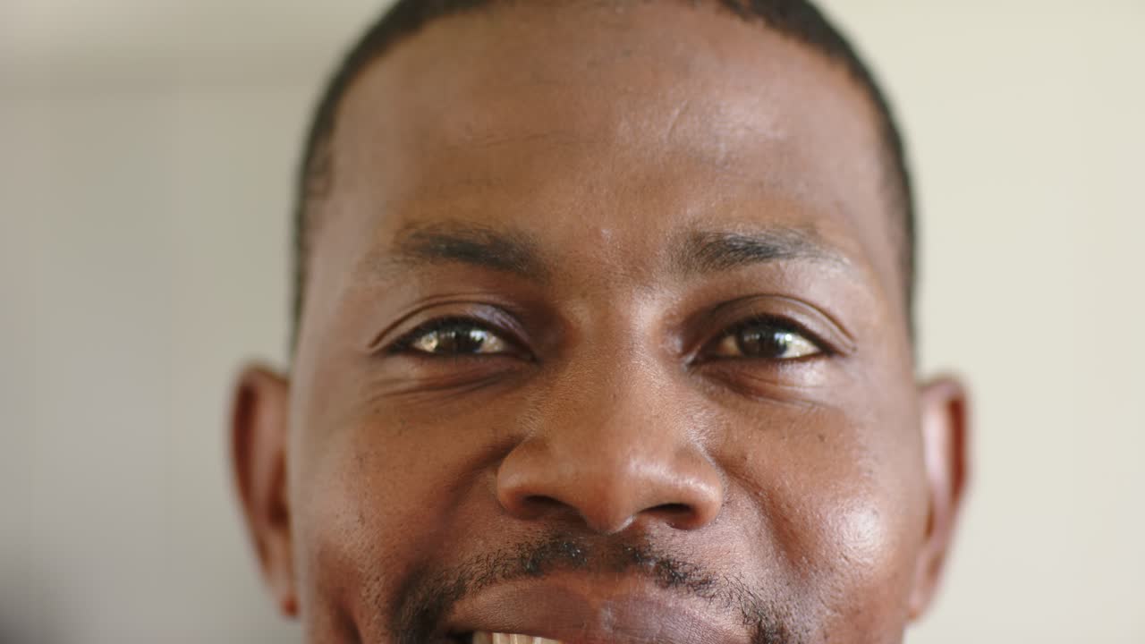 African American man blinking, revealing face indoors, rotating head forward meeting gaze for smile