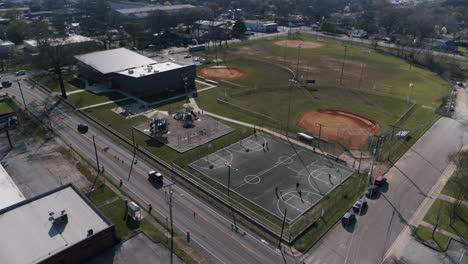 Aerial-pan-across-a-recreation-field-with-basketball-courts-and-playground-equipment-being-used-by-people-in-the-neighborhood-in-Chattanooga,-TN