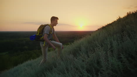 the guy the teenager with a backpack climbs up the mountain at sunset active way of life since youth