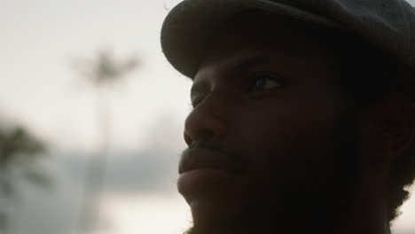 close-up of a young black man on an exotic beach with palm trees in the background