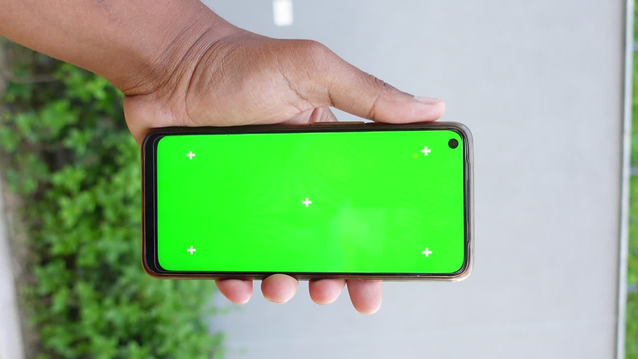 mano sosteniendo un teléfono inteligente con una pantalla verde