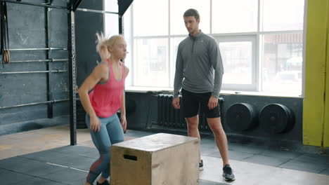 woman performing box jumps with personal trainer in gym