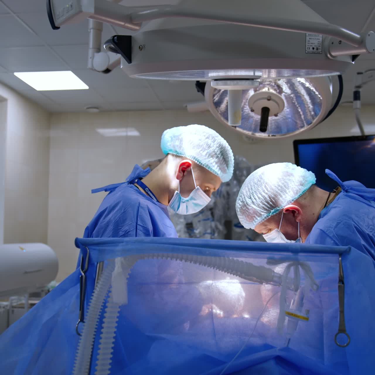 Allontanamento dal tavolo operatorio dove lavorano due chirurghi. Medici caucasici di sesso maschile chini sul paziente che eseguono la procedura