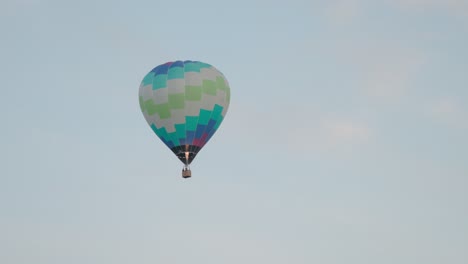 a vibrant hot air balloon lifts off into the sky as its burner fires, creating a warm glow against the morning light at the canberra balloon spectacular.