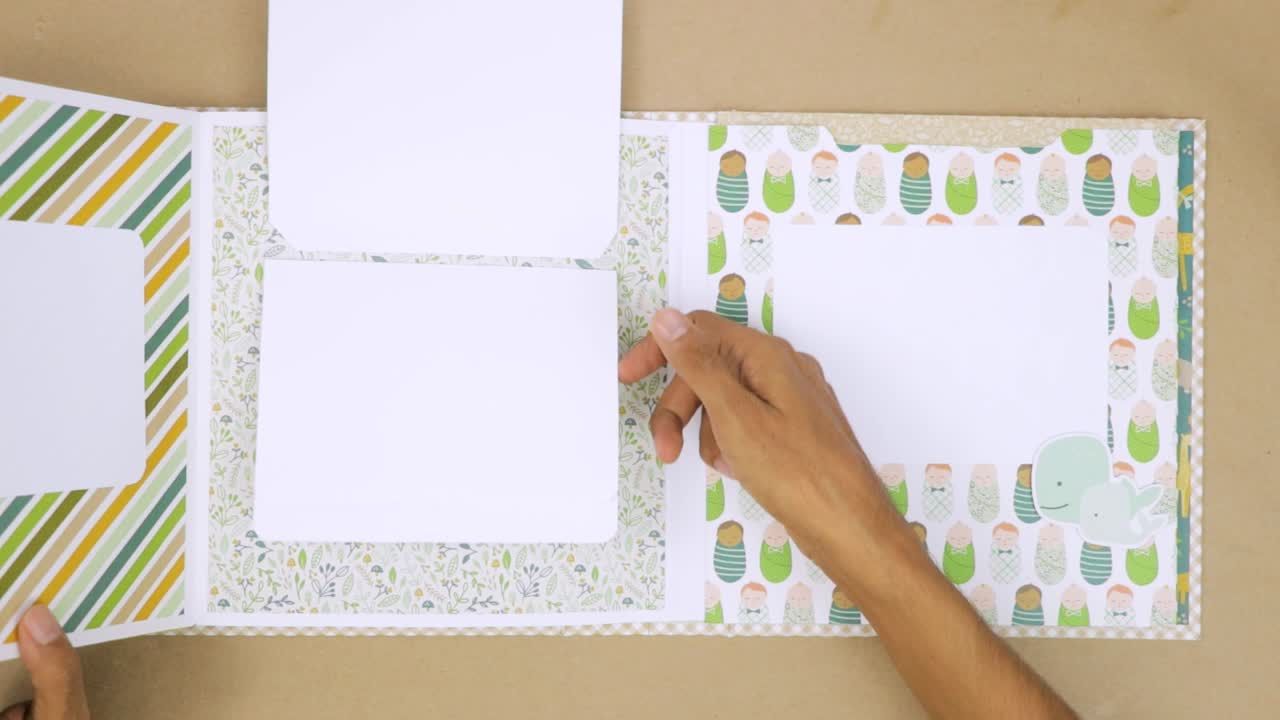 아기 테마 스크북 앨범의 페이지를 뒤집고, 재미있는 디자인으로 사진 배치를 위한 다른 섹션을 레이아웃합니다.