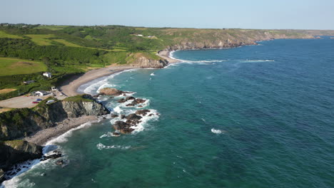 Waves-breaking-on-the-rugged-coastline-of-South-Cornwall,-England-seen-from-a-drone-point-of-view