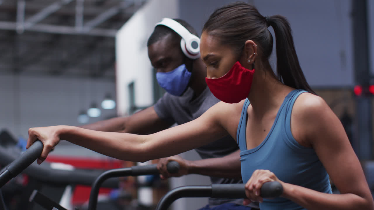Mixed race woman wearing face mask exercising at gym