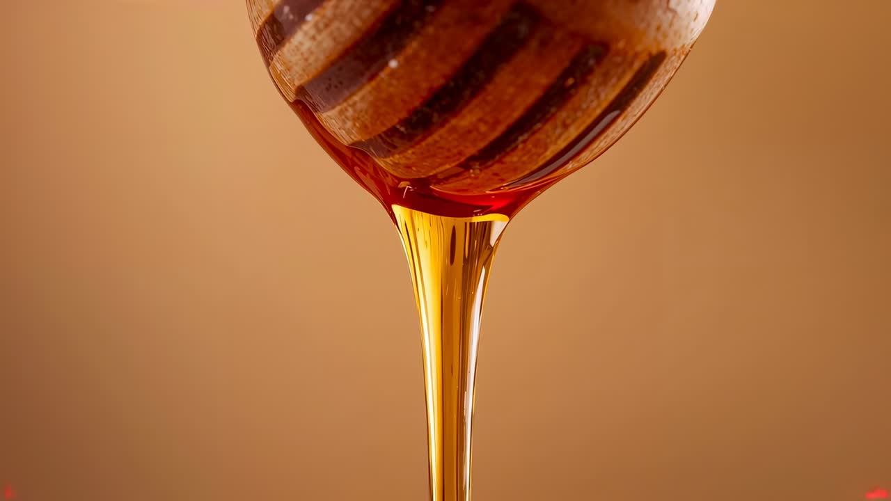 Mestolo in legno per miele che rilascia una goccia di miele viscoso in un flusso lucido in cucina, mentre la gravità lo attrae