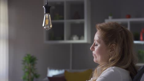 Idea-lamp.-Mature-business-woman-thinks-about-idea-and-idea-lamp-flashes.