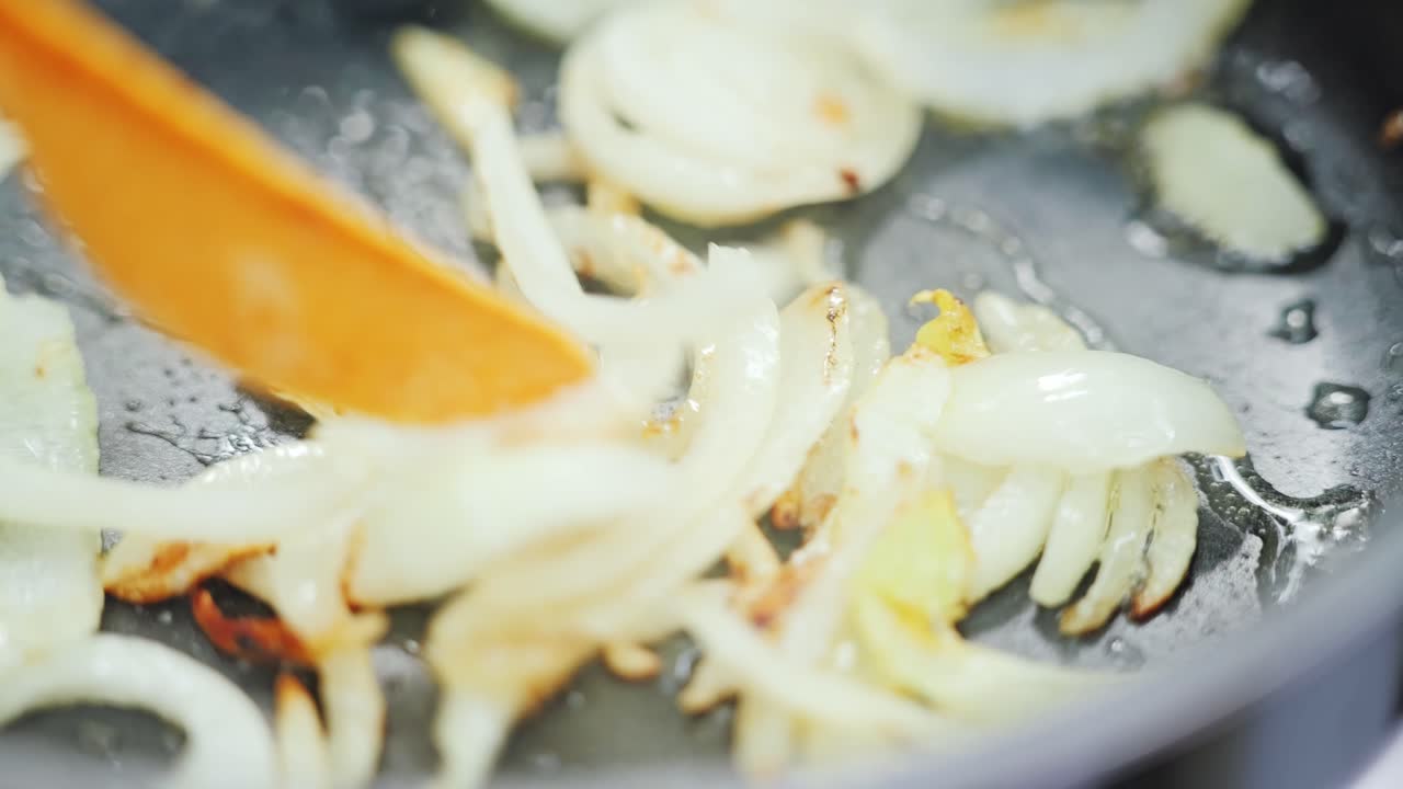 Golden onions cooking in camping stove pan with rustic atmosphere slow motion
