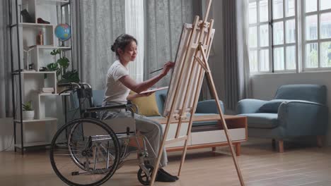 mujer en silla de ruedas pintando en casa