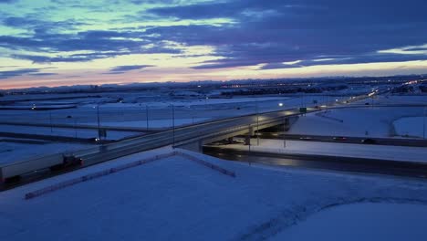 dusk aerial of snowy overpass with lonely traffic and evening cloud