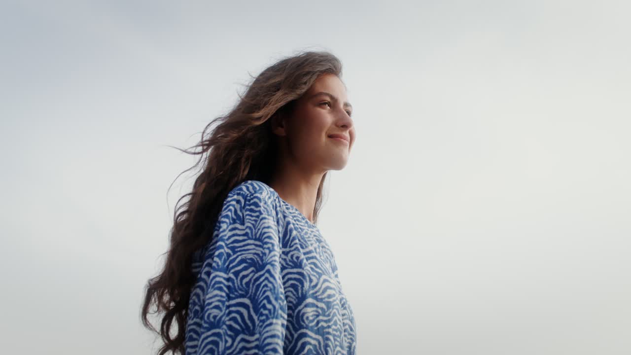 una mujer de cabello largo mirando hacia el cielo.