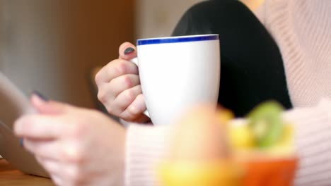 mujer usando el teléfono móvil mientras toma café