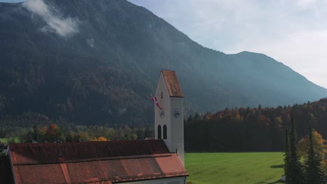 a serene drone orbit of a historic church tower nestled among the majestic peaks of the austrian alps