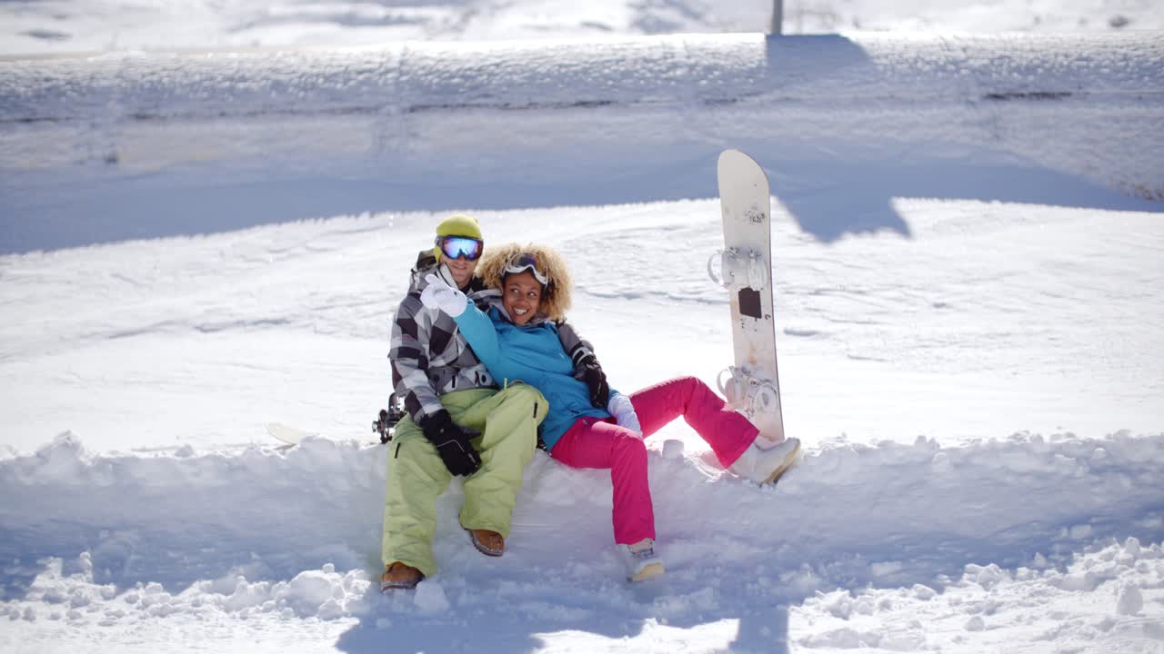 una pareja feliz sentada en un profundo estante de nieve