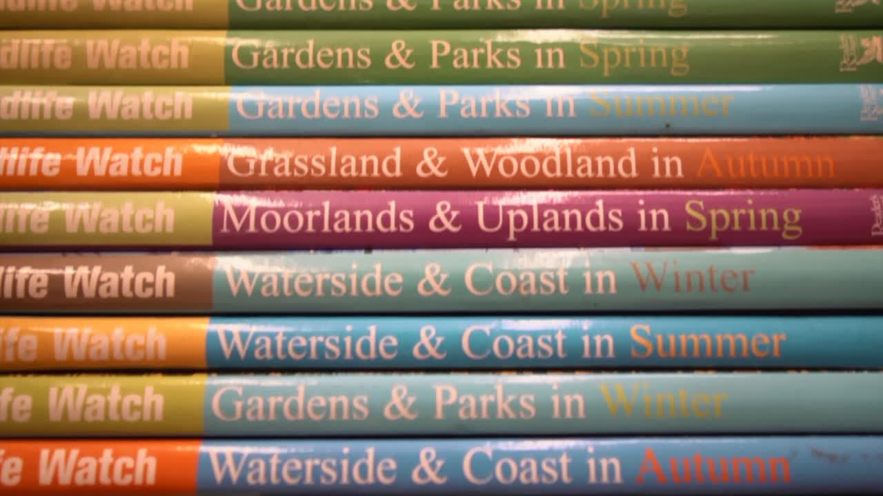 나무 선반에 있는 야생 동물 시계 책 볼륨 스택의 근접 추적