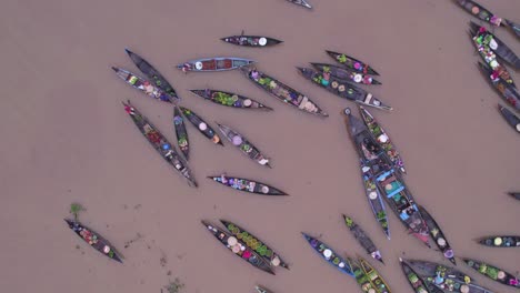 top down of slow moving wooden boats full of food at lok baintan floating market, aerial