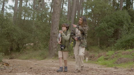 femme caucasienne et son fils marchant le long d'un chemin de terre dans un parc naturel, explorant la nature et la faune