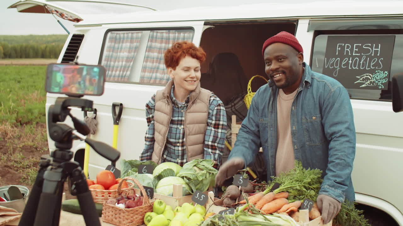 agricultores multiétnicos filmando un anuncio de video del mercado de verduras al aire libre con un teléfono