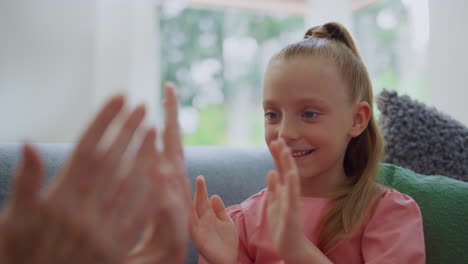 Portrait-of-pretty-girl-playing-with-grandmother-hands-in-living-room