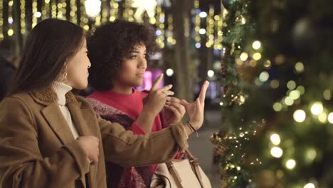 two women admire a christmas tree at night