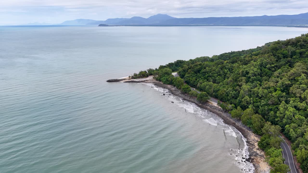 Drone footage captures the serene coastline of Daintree Rainforest, showcasing lush greenery and calm ocean waters under soft daylight