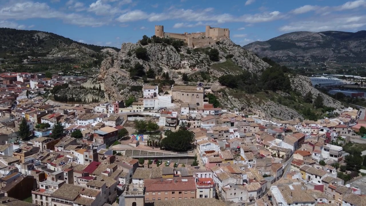 Volando sobre el casco antiguo hacia el castillo islámico en la cima de la colina. Castalla, España
