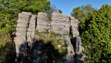 Aged-rock-cliff-surrounded-with-green-vegetation,-motion-view