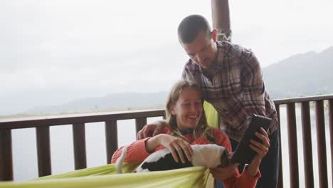 caucasian couple spending time at home playing with a dog, the woman using a tablet