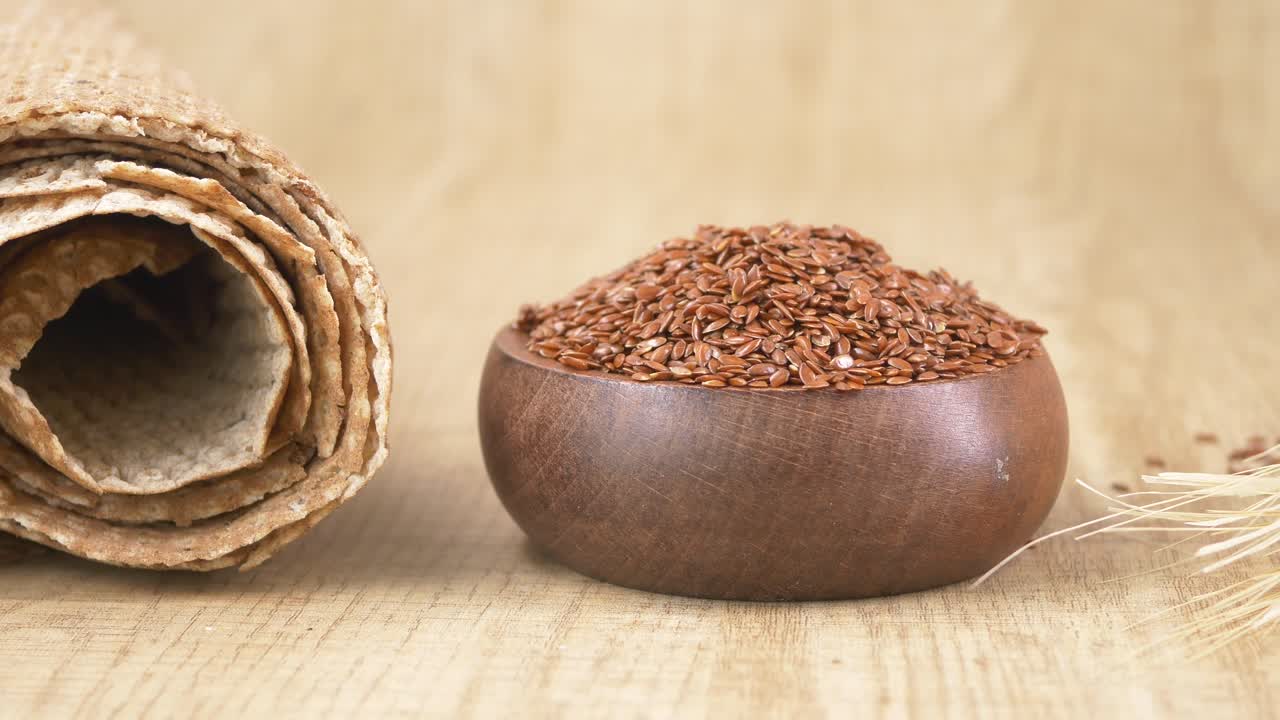 Flax Seeds in Wooden Bowl with Flatbread and Wheat Stalks