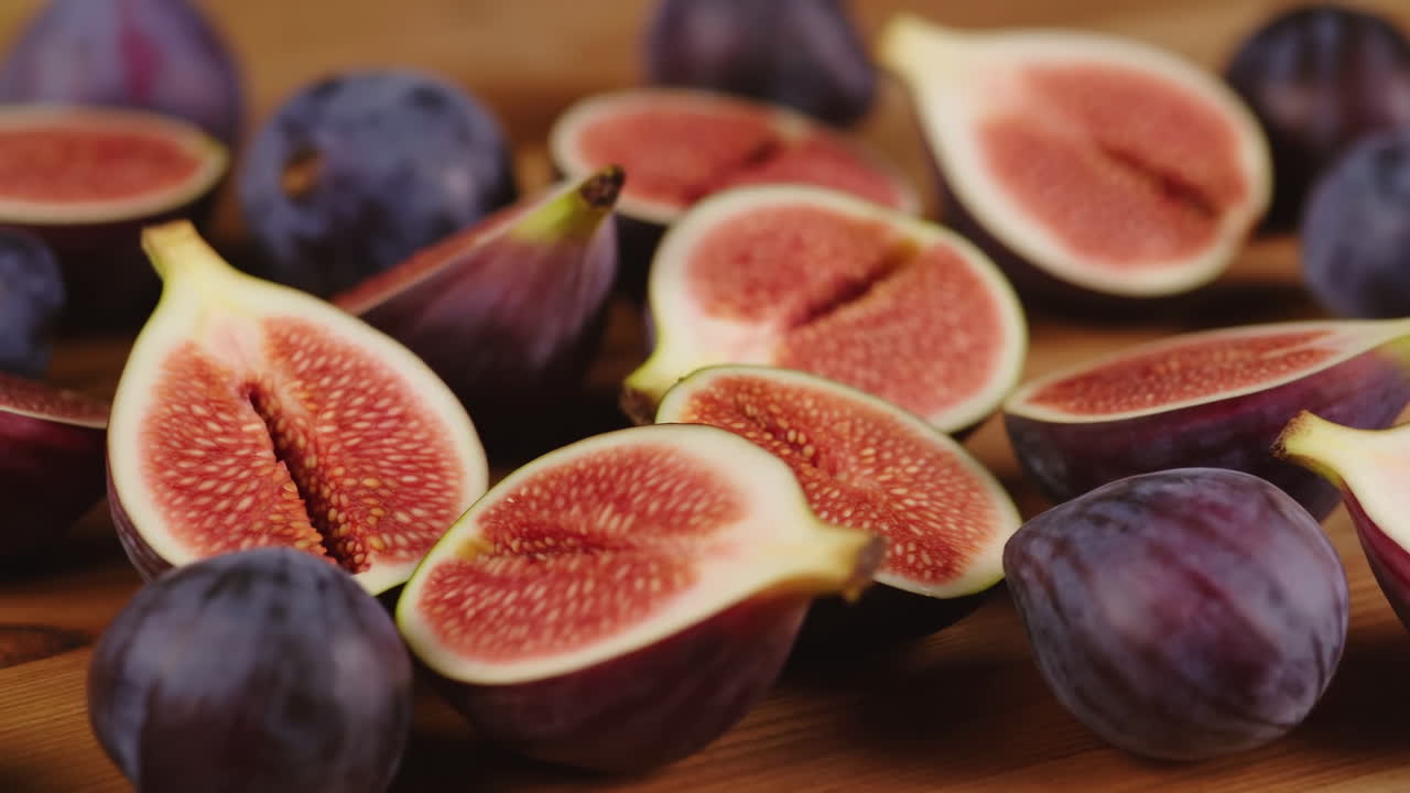 Primer plano de higos maduros en rodajas revelando sus interiores sobre una tabla de madera, con luz natural cálida y poca profundidad de campo.