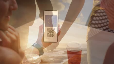 mujer sosteniendo un teléfono inteligente con código qr en la pantalla contra una pareja de manos en la playa