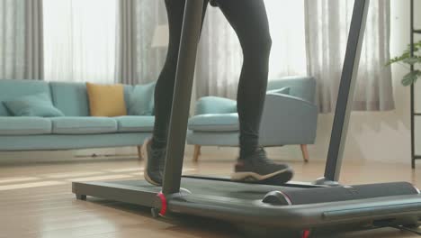 legs of asian woman running on a treadmill at home