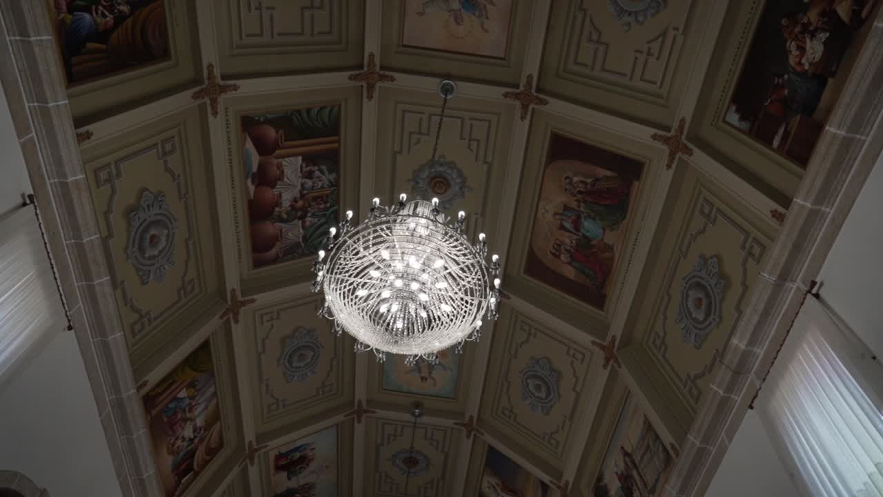 Lampadario di cristallo sospeso da pannelli decorati del soffitto di una chiesa.