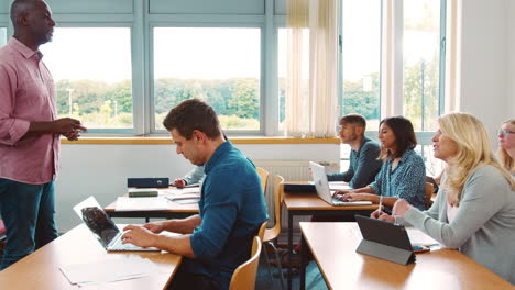 male tutor standing to teach class of mature students