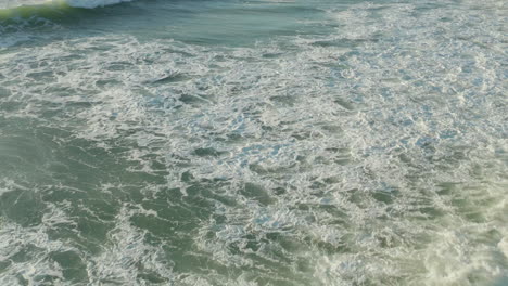 Hermosas-Olas-De-Surf-Blancas-Y-Verdes-A-La-Luz-De-La-Tarde,-ángulo-Bajo-Aéreo-A-Vista-De-Pájaro,-Inclinación-Hacia-Adelante