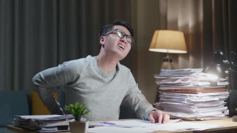 집 에서 문서 를 열심히 처리 하는 동안 허리 통증 을 겪는 아시아인