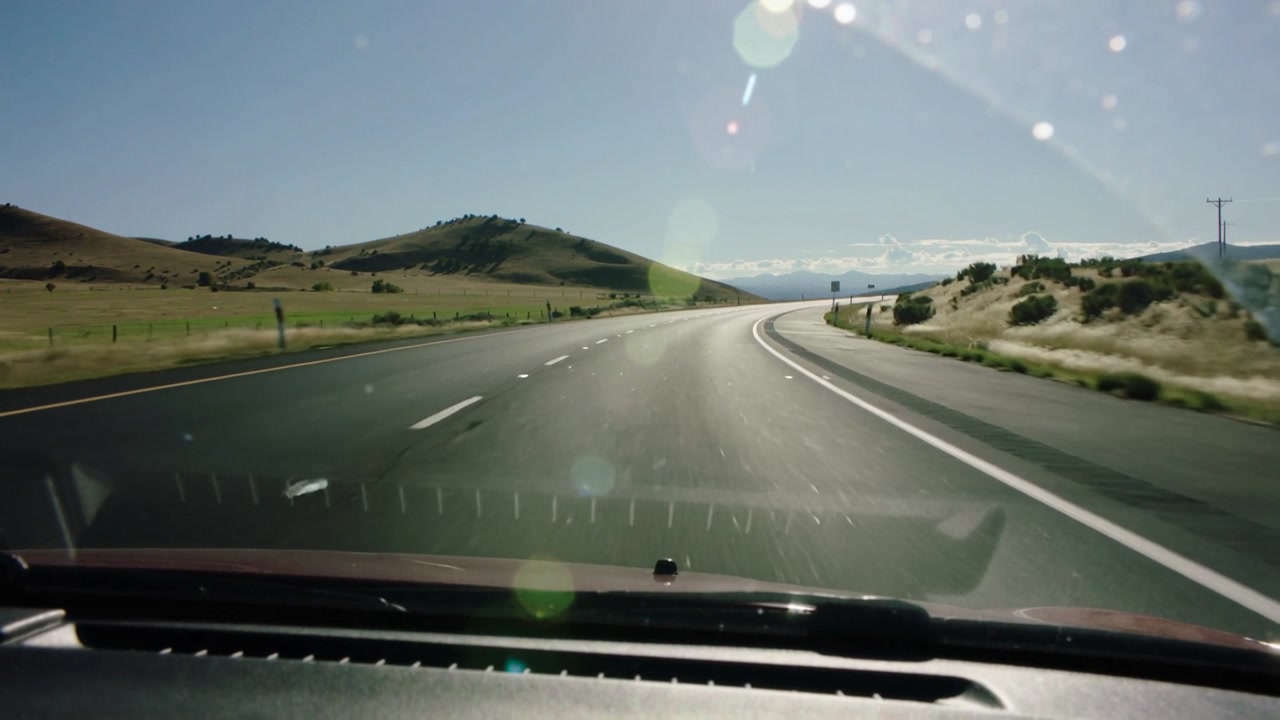 Driving car entering right curve, dashcam capturing forward road, dash, lane lines heading to hills