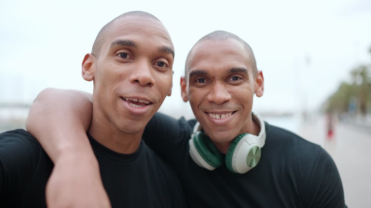 Two smiling brothers recording video at camera and talking
