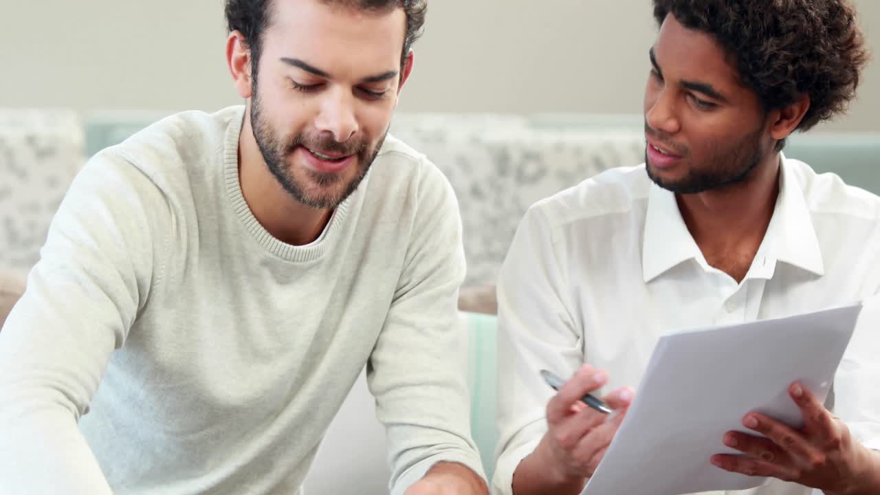 계산기를 사용하는 동성애 커플이 청구서를 지불하고 있습니다.