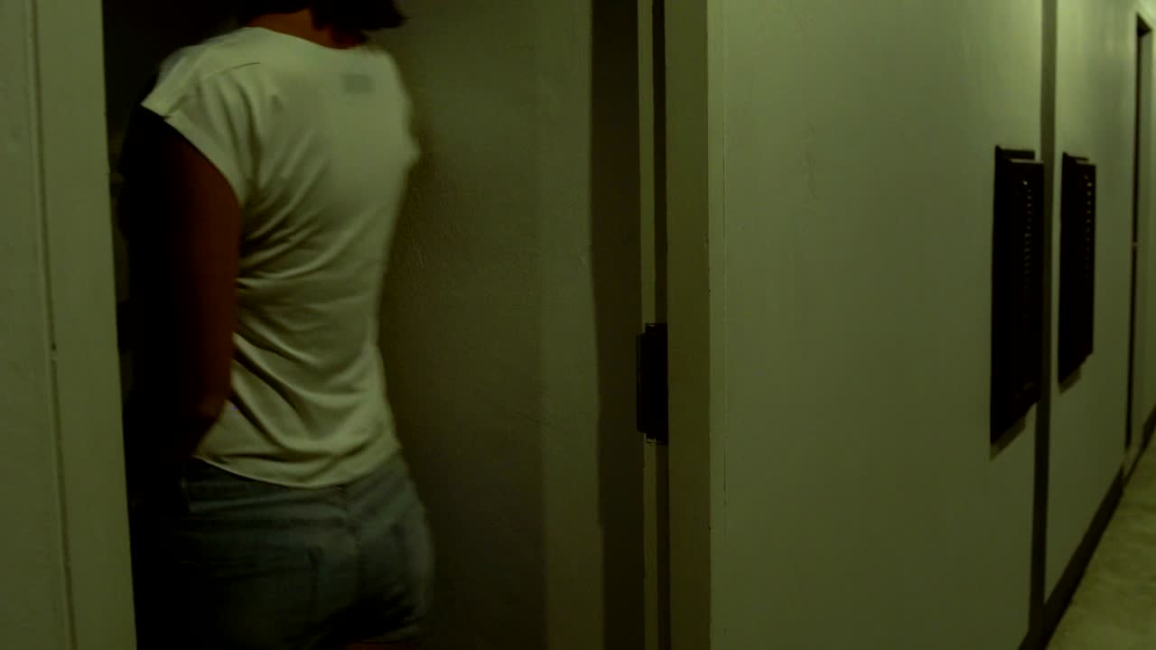 The woman approaches the door of the hotel room, applies a key card and enters the room