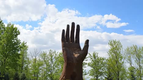 a large wooden hand on top of a green hill