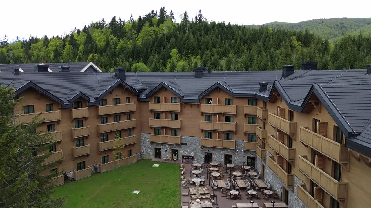 Modern wooden chalet surrounded by lush pine forest in summer, Biogradska Gora National Park, Swissotel resort, Drone