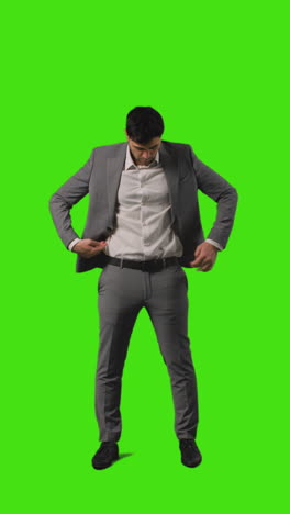 Vertical-Video-Full-Length-Shot-Of-Businessman-Standing-Against-Green-Screen-Straightening-And-Adjusting-Suit-Against-Green-Screen-1