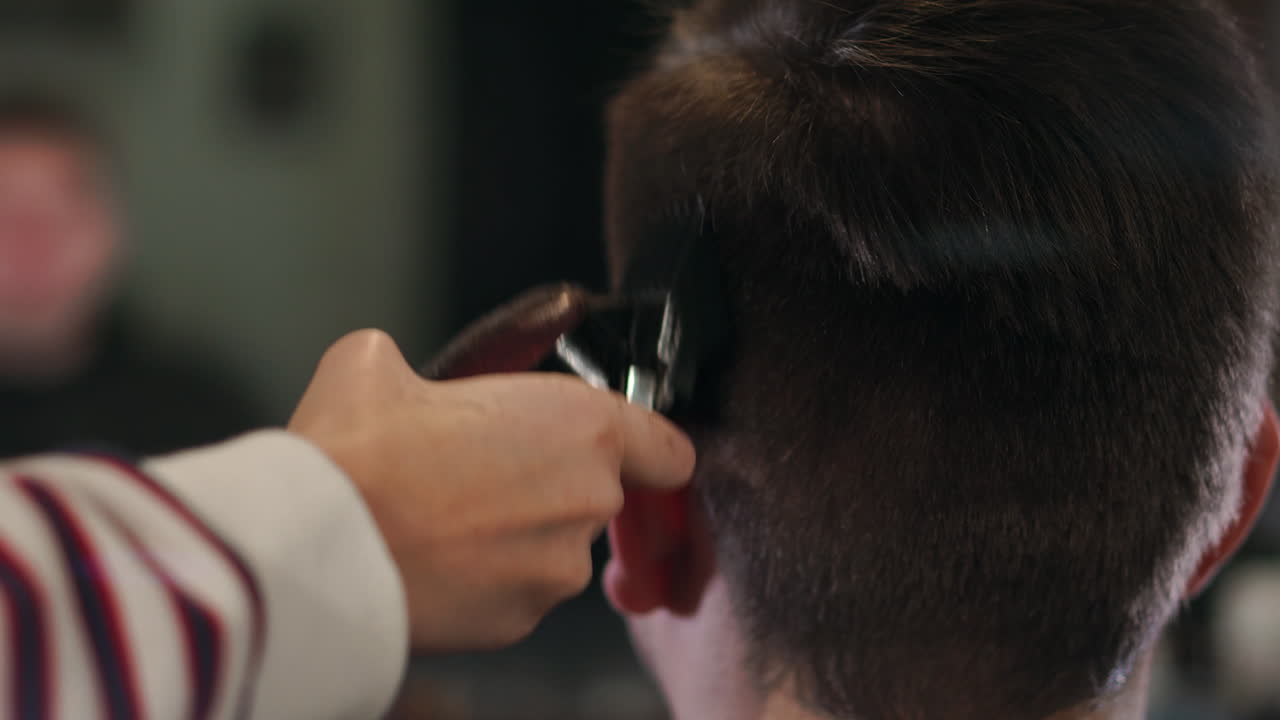 Hairdresser tools. Close up of male hands brushing electric hair clippers. Hairdressers prepare hair machine for next client. Man clean black shaving machine
