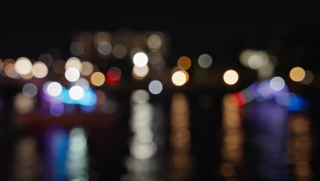 colorido bokeh de luces de vacaciones que se reflejan en el agua durante un desfile de barcos de navidad en el río por la noche