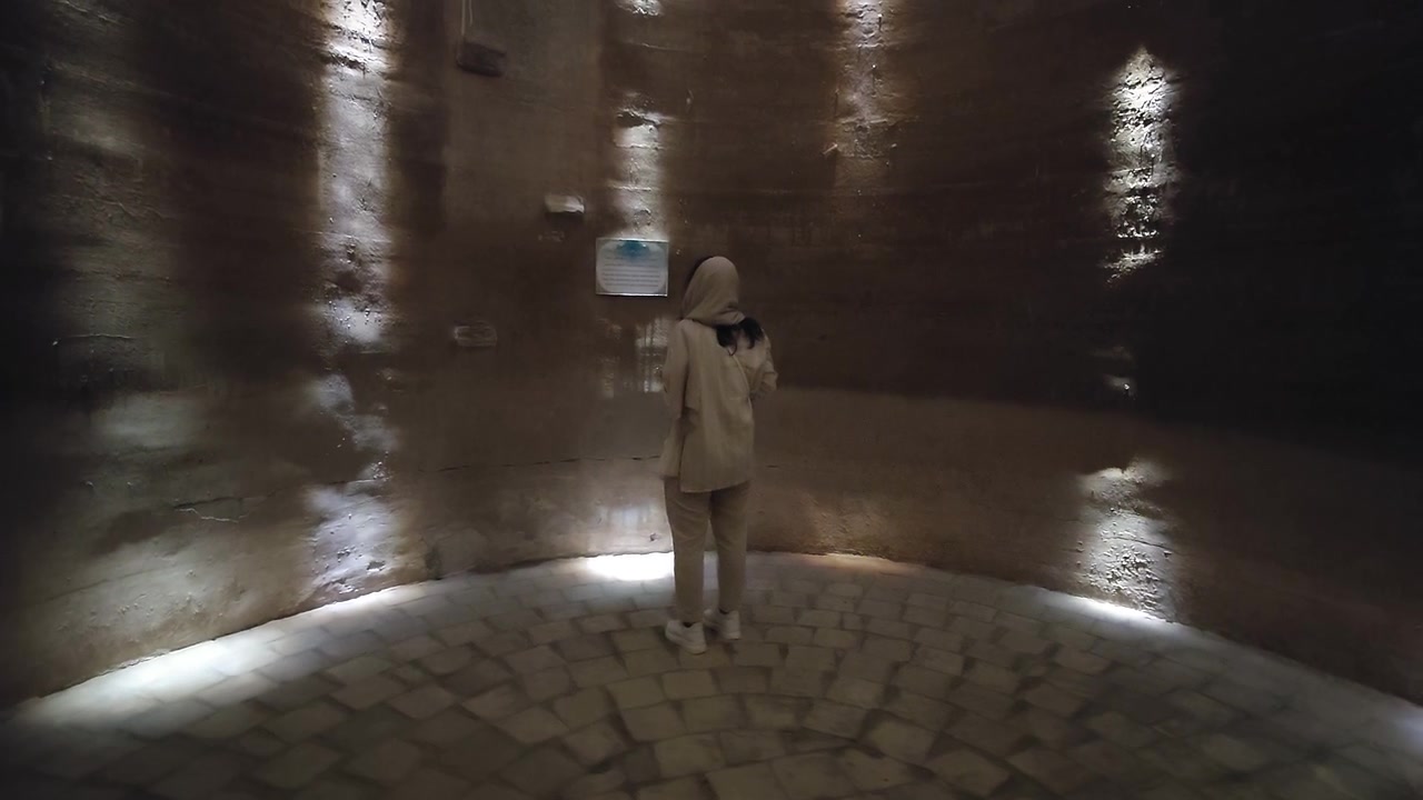 Donna che esplora una camera circolare in pietra scarsamente illuminata